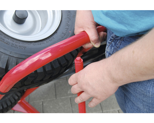 Nahaufnahme eines Mannes, der eine rote Schubkarre montiert.