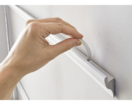 Anbringen einer Zierleiste mit Klebeband an der Wand