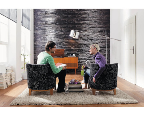 Wohnzimmer mit zwei Personen in Sesseln, Stehlampe und Dekoration auf einem Teppich