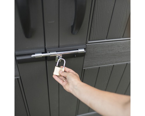 Eine Person verschließt einen Geräteschuppen mit einem Vorhängeschloss.