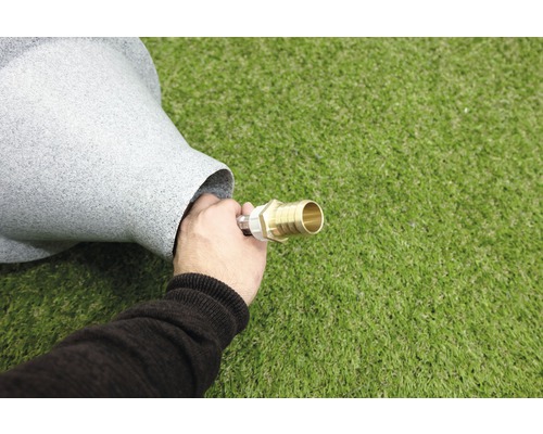 Ein Mann verbindet einen Wasserschlauch mit einem grauen Springbrunnen.