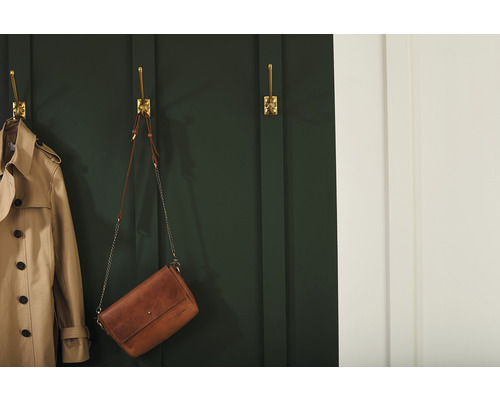 Szene mit einem Trenchcoat und einer Handtasche, die an goldenen Wandhaken hängen