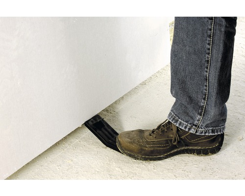 Eine Person verwendet einen Montagefuß, um eine Gipskartonplatte anzuheben.