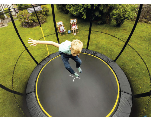 Junge springt auf einem Gartentrampolin mit Sicherheitsnetz