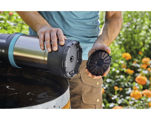 Ein Mann setzt einen Filter in eine automatische Regentonnenpumpe