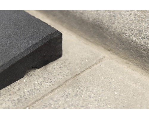 Detailaufnahme einer schwarzen Gummimatte auf einer Betonoberfläche