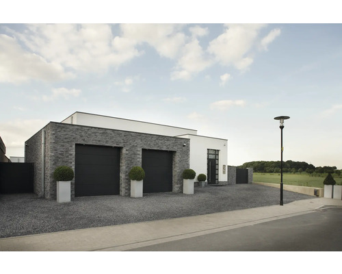 Außenansicht eines modernen Hauses mit Garage, Steinfassade und gepflasterter Auffahrt