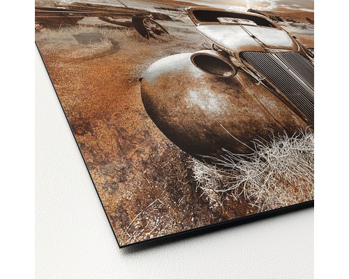 Detailaufnahme eines Drucks mit dem Motiv eines alten, verrosteten Autos auf einem Feld