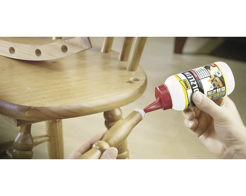 Eine Person klebt mit Holzleim einen Holzstuhl.