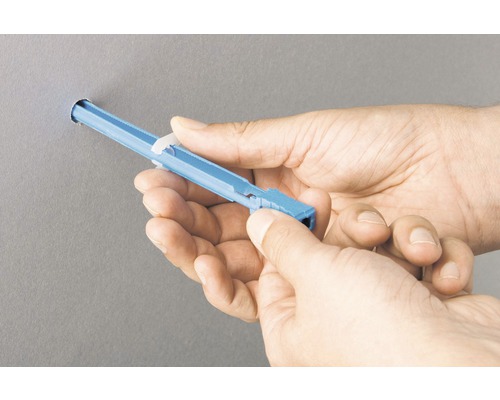 Person setzt eine Hohlraumdübel in eine Wand