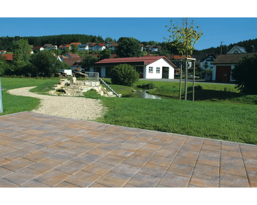 Verlegte Pflastersteine im Außenbereich mit einem kleinen Bach und Häusern im Hintergrund