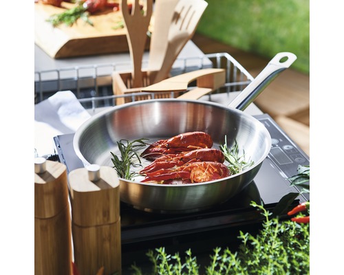 Edelstahlpfanne mit Flusskrebse und Rosmarin auf einem Kochfeld
