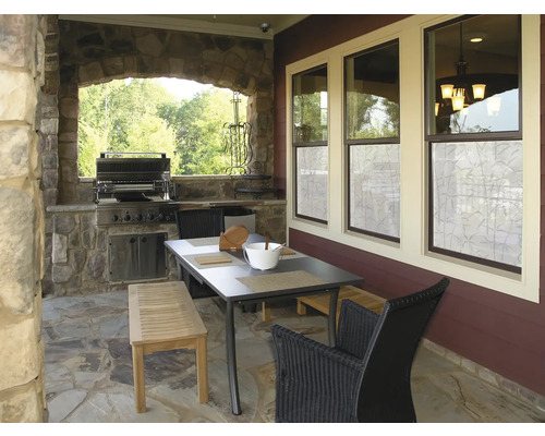Überdachte Terrasse mit Grill, Tisch, Bank und Stühlen.