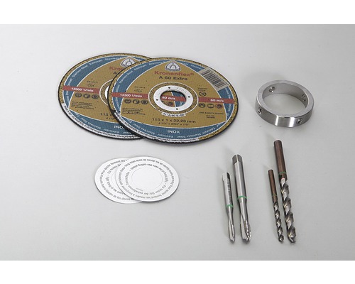 Zwei Trennscheiben, ein Metallring, Gewindebohrer und Spiralbohrer auf einer hellen Oberfläche