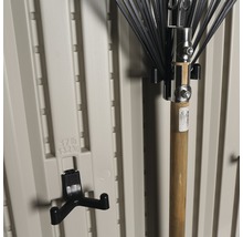 Gartengerätehalter und Laubrechen an einer Kunststoffwand.