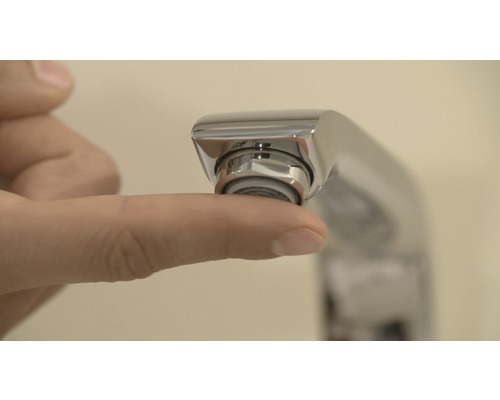 Detailaufnahme einer Hand, die einen Wasserhahn-Luftsprudler berührt