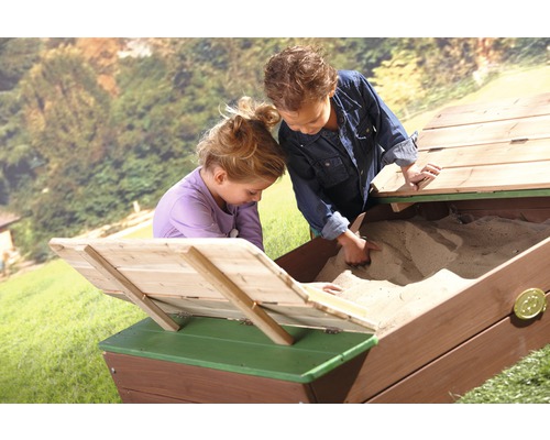 Zwei Kinder spielen in einem Sandkasten aus Holz mit Deckel