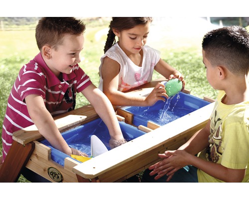 Kinder spielen an einem hölzernen Sand- und Wassertisch im Freien