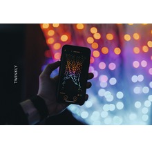 Hand hält ein Smartphone mit der Twinkly App vor Lichtern