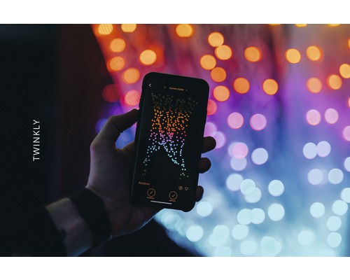 Hand hält ein Smartphone mit der Twinkly App vor Lichtern