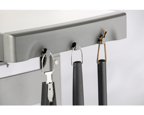 Grillutensilien hängen an einem Grill