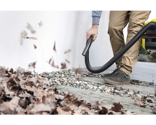 Person entfernt Blätter mit einem Laubsauger von einem Gehweg