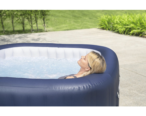 Frau entspannt in einem aufblasbaren Whirlpool im Garten.