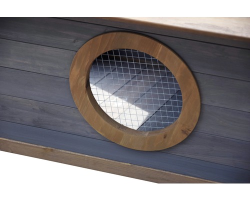 Detailansicht eines runden Fensters mit Gitter in einem Holzhaus