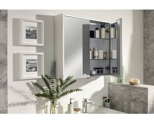 Badezimmer mit Spiegelschrank, Waschbecken und dekorativen Elementen für eine helle und organisierte Atmosphäre