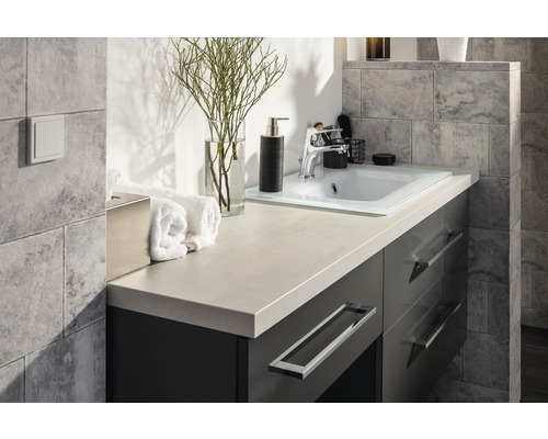 Badezimmerwaschtisch mit Waschbecken, Armatur und Dekorationsartikeln.