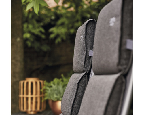 Nahaufnahme von grauen Gartenmöbelkissen mit Pflanzen im Hintergrund