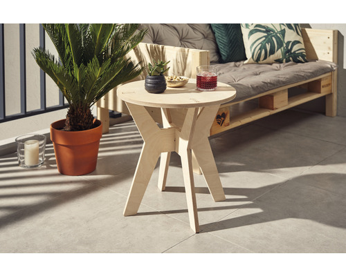 Holzbeistelltisch mit Getränk, kleinem Topf und Snacks auf einem Balkon mit Pflanze und Palettensofa