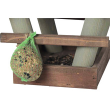 Vogelfutterknödel in einem grünen Netz an einem hölzernen Vogelhaus