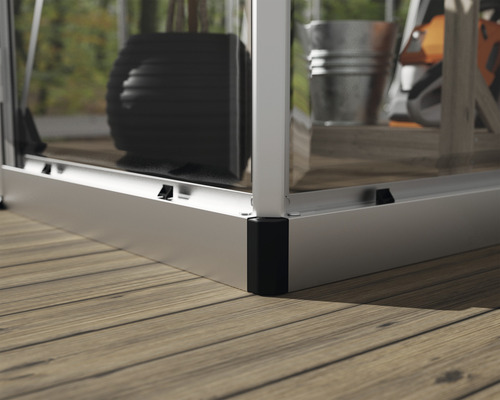 Detailansicht eines Gewächshauses auf einem Holzdeck mit Metallrahmen und Glaseinsätzen.
