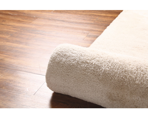 Detailansicht eines gerollten Teppichs auf Holzboden