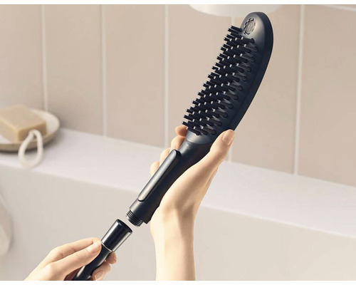 Brausekopf mit Bürste und Schlauchanschluss in der Hand