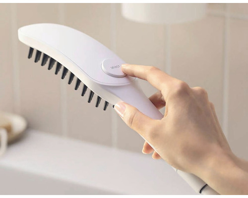 Eine Hand bedient eine weiße Bürste mit schwarzen Borsten.