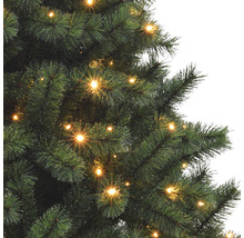 Detailaufnahme eines beleuchteten künstlichen Weihnachtsbaums mit Tannenzweigen