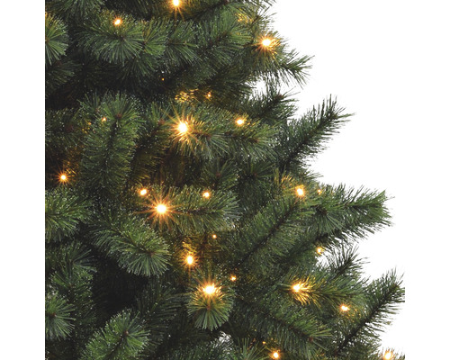 Detailaufnahme eines beleuchteten künstlichen Weihnachtsbaums mit Tannenzweigen