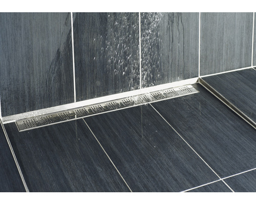 Detailaufnahme eines Duschbereichs mit einer Edelstahl-Duschrinne und dunklen Fliesen