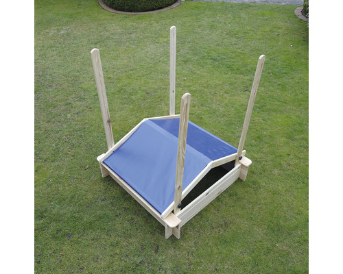 Sandkasten mit Holzrahmen und blauem Sonnenschutz auf einer Wiese.