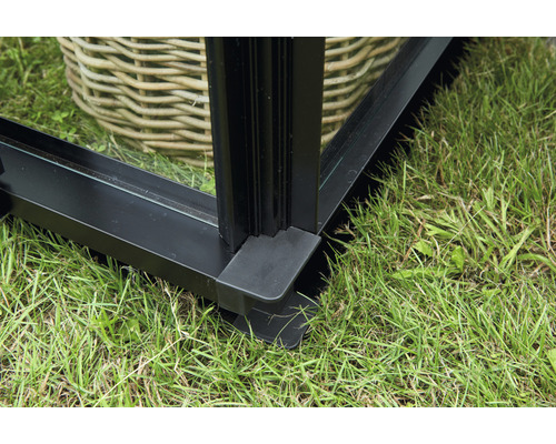 Detailansicht eines Gewächshauses aus Glas und Metall auf einer Grasfläche.