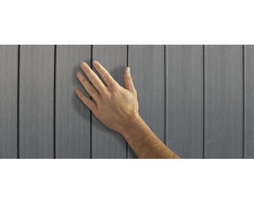 Hand berührt graue Fassadenverkleidung aus Kunststoff.