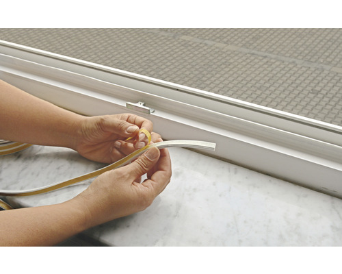 Hände entfernen Schutzfolie von Dichtungsband am Fenster