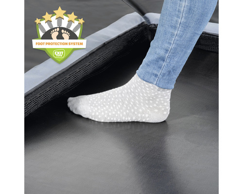 Detailaufnahme eines Trampolins mit Fußschutzsystem und Fuß einer Person mit Socken