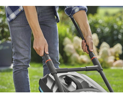 Eine Person bedient einen Rasenmäher im Garten.