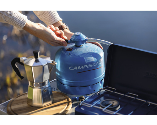 Campingkocher mit Gaskartusche und Espressokocher auf einem Tisch im Freien.