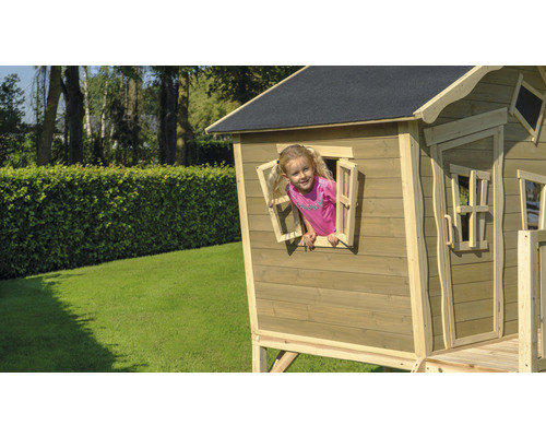 Kind spielt in einem hölzernen Spielhaus im Garten