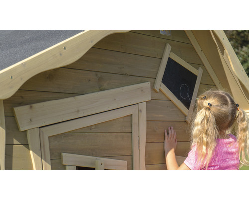 Kind malt auf einer Tafel an einem Holzspielhaus