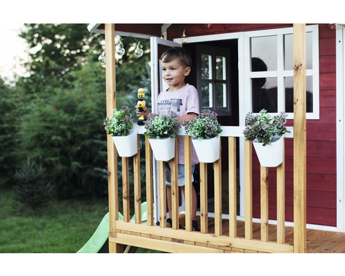 Spielhaus mit Junge, Blumenkästen und Spielzeug auf der Veranda im Garten